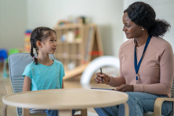 A female therapist of African decent, sits with a little girl as they discuss some of her struggles at home, at school and with her peers.